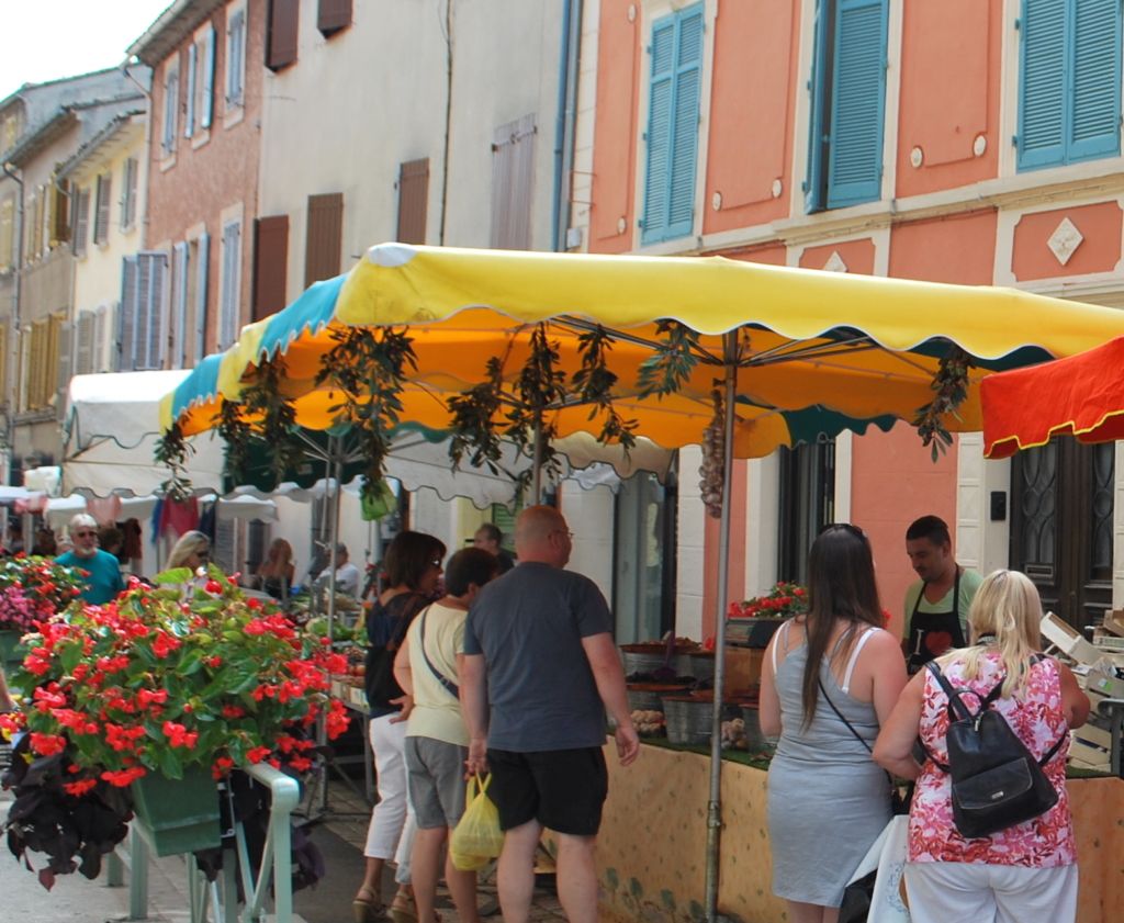 Provençal market in Le Beausset with colourful flower stalls and umbrellas in front of pastel façades