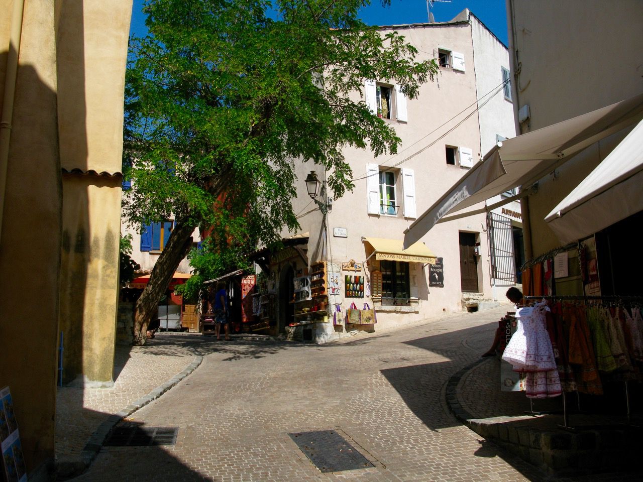 Shop-lined alley in Le Castellet with local artist workshops, galleries and small terraces under the trees
