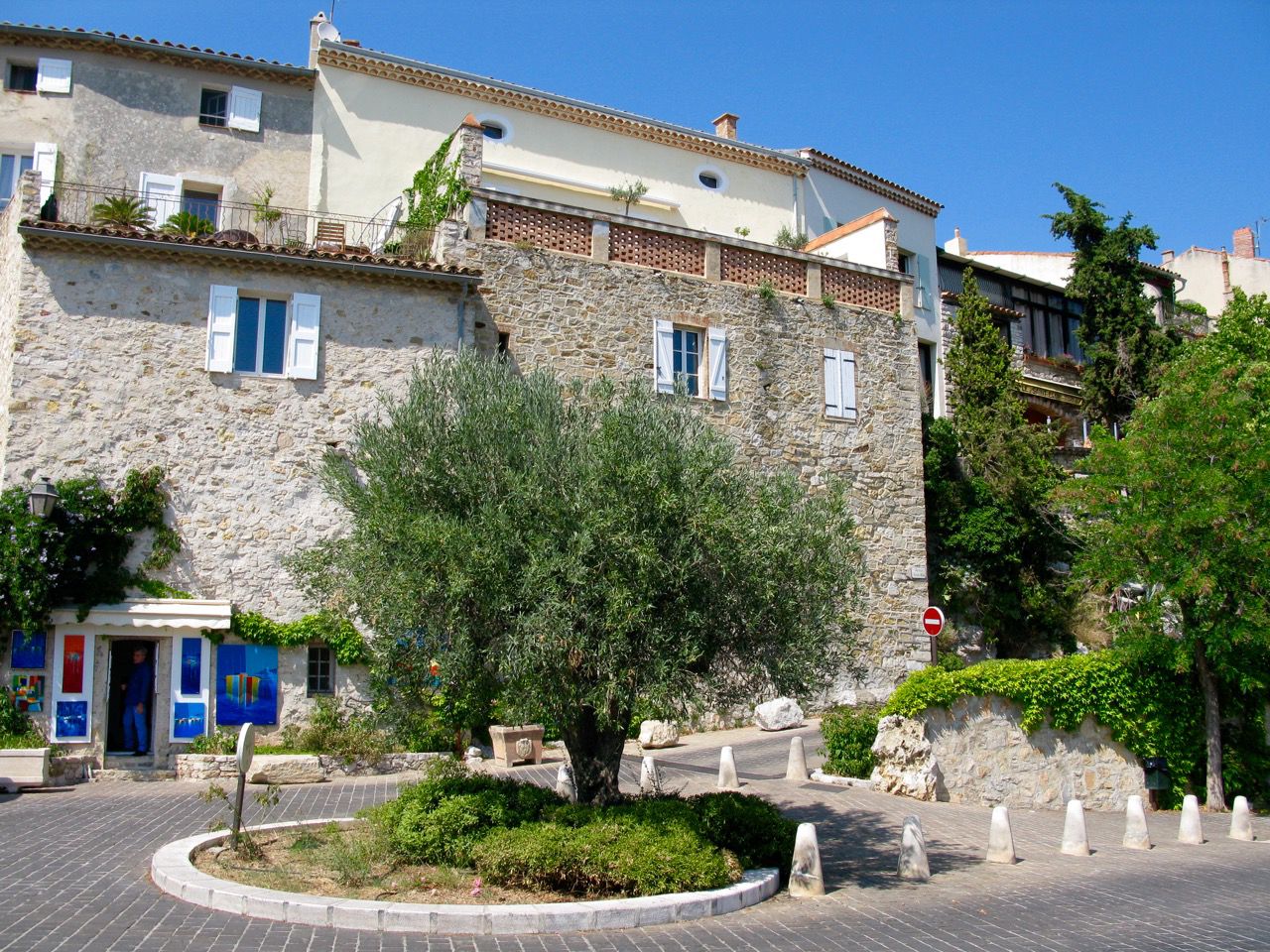 Medieval alley in Le Castellet with light stone façades, olive tree and a small cobbled square at the heart of the hilltop village
